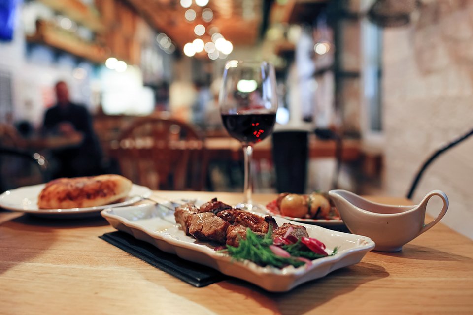 A roast dinner with gravy and a glass of wine on a restaurant table.